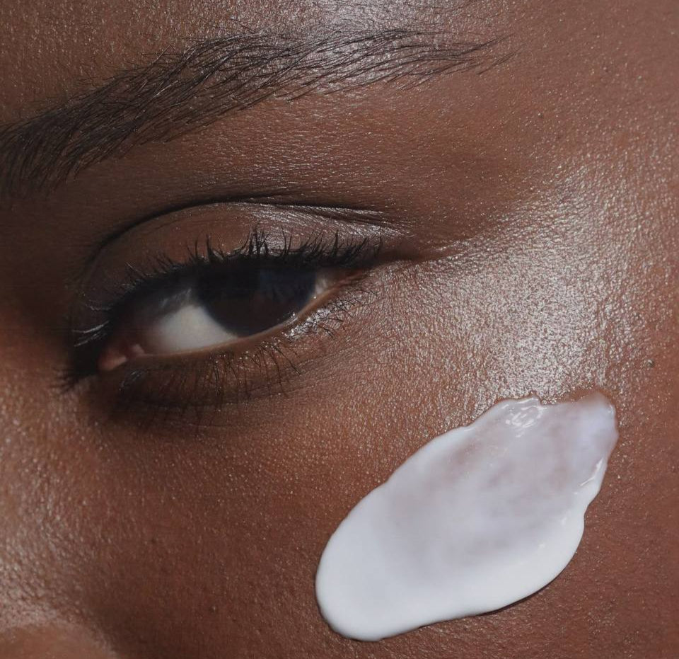 Close-up of a woman's face with a skincare product applied to her cheek.